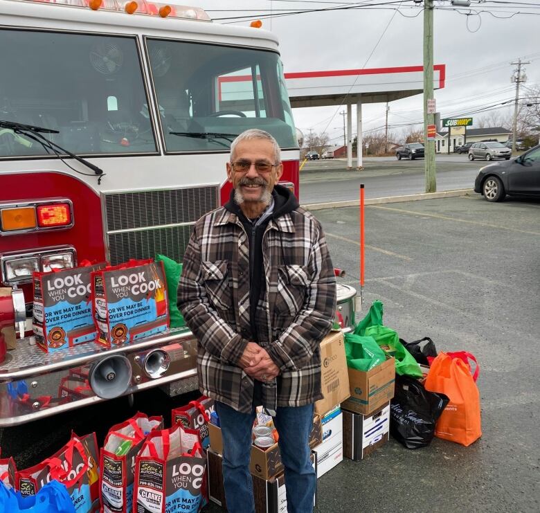 A man poses in front of a firetruck.