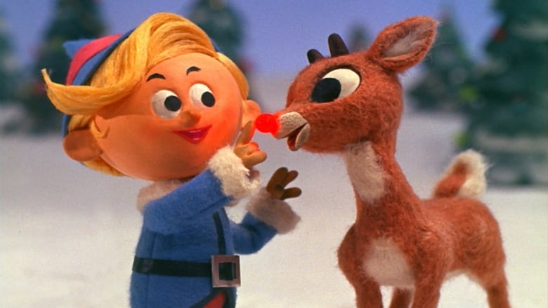 A still from the animated 1964 film Rudolph the Red-Nosed Reindeer: Rudolph the Red-Nosed Reindeer next to Hermey the Elf in a blue suit, in the snow.