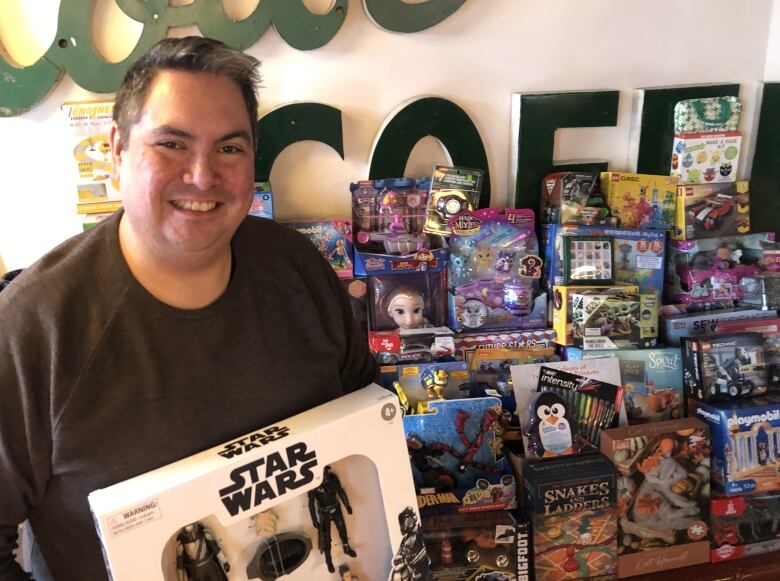 A man poses with a pile of toys.