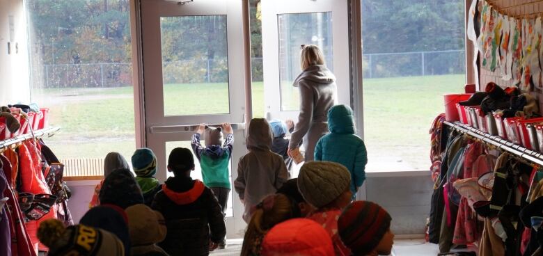 Two rows of kids wearing coats and hats line up to go outside and play at the Echo Bay public school outside of Sault Ste. Marie. 