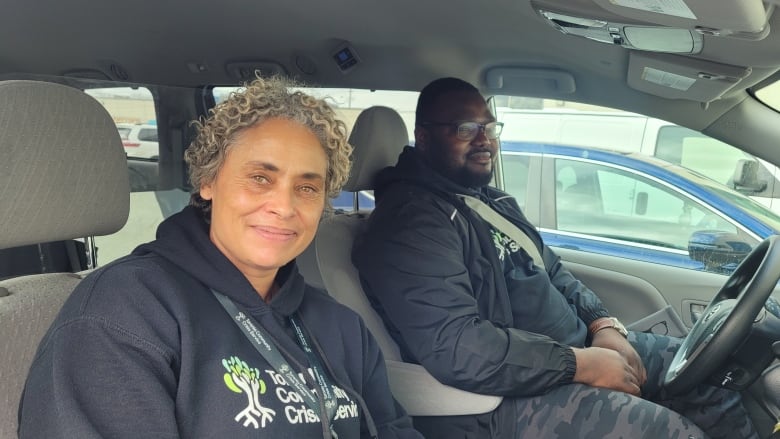 Two people sit in front seat of a car. 