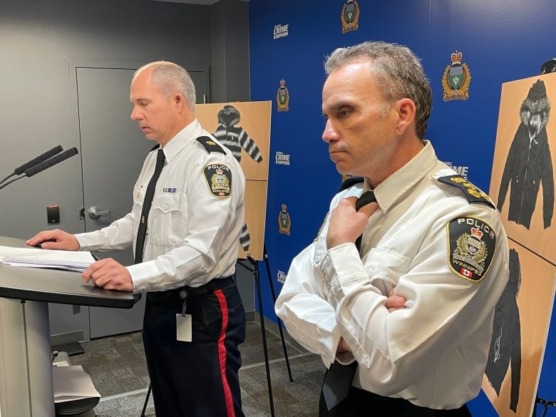 Two uniformed police officers stand at a podium with photos of a jacket in the background.