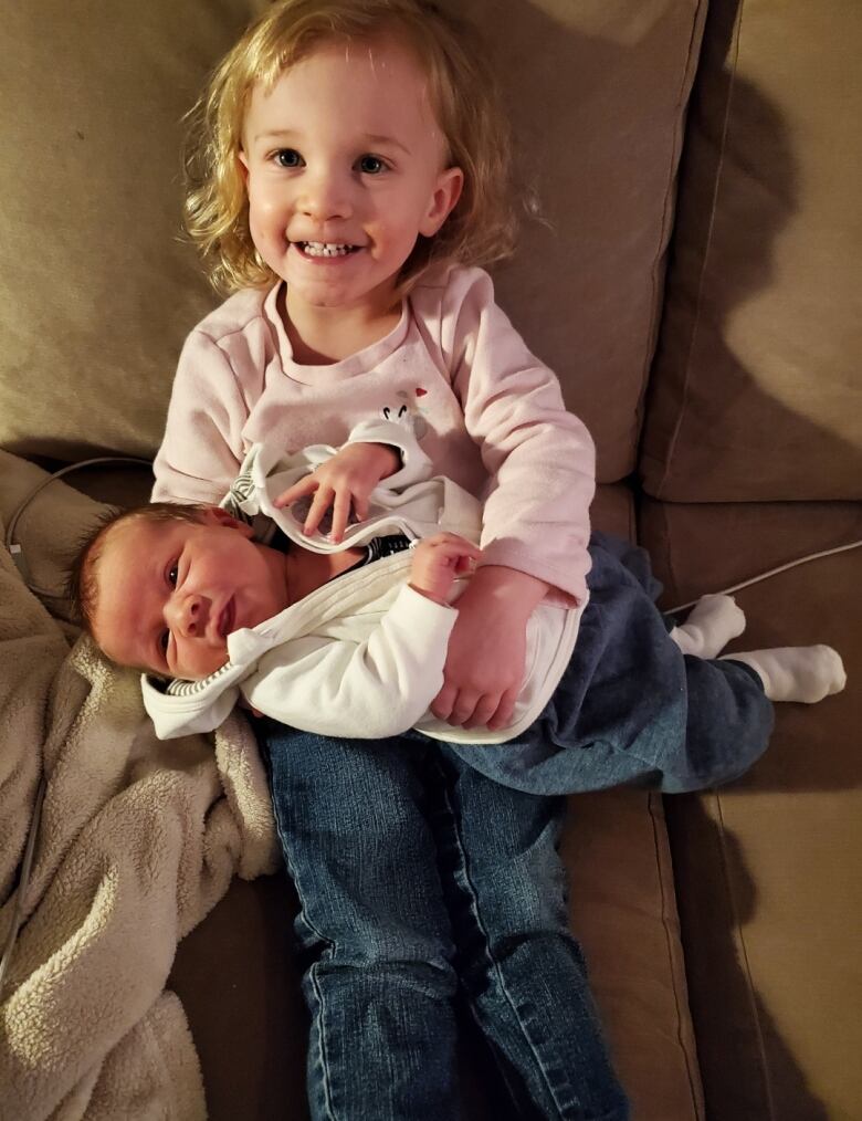 A young girl is pictured with her baby brother on her lap. 