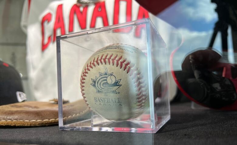 A baseball sits in a glass case.