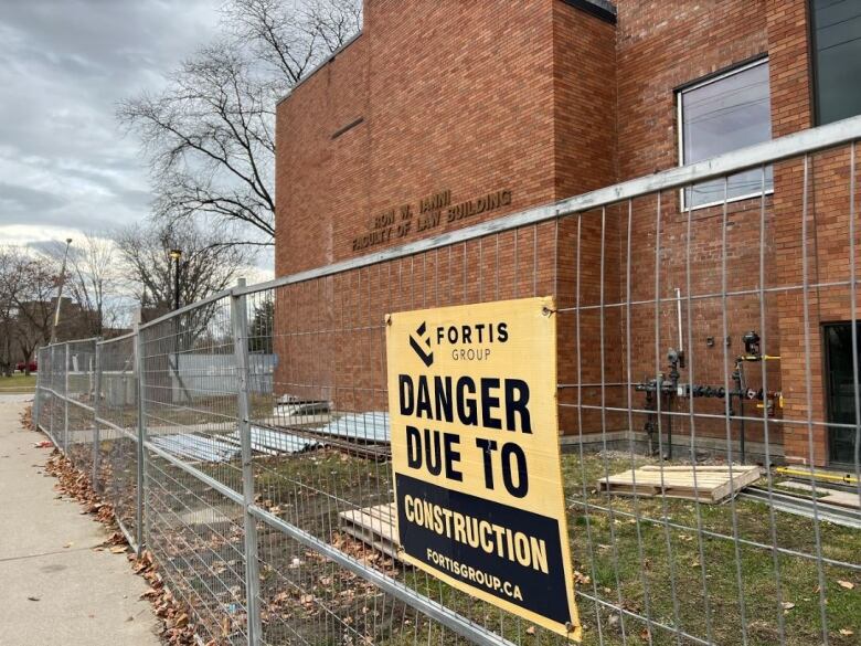 A brick building, with a steel gate infront that has a 'Danger Due to Construction' sign.