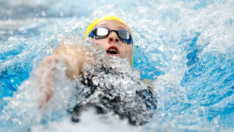 A women's swimmer competes in the backstroke.