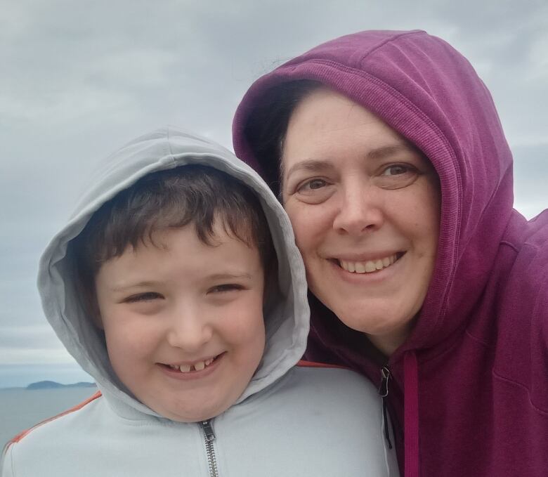 A young boy, left, and a middle-aged woman smile into the camera.