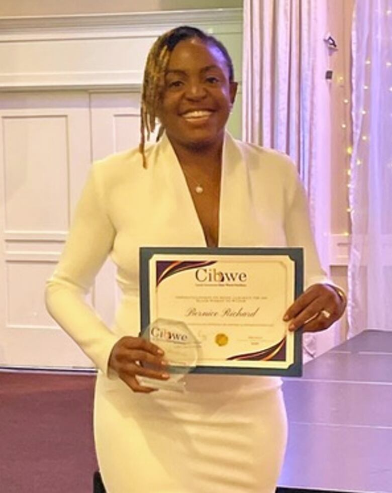 A smiling woman poses with an award.