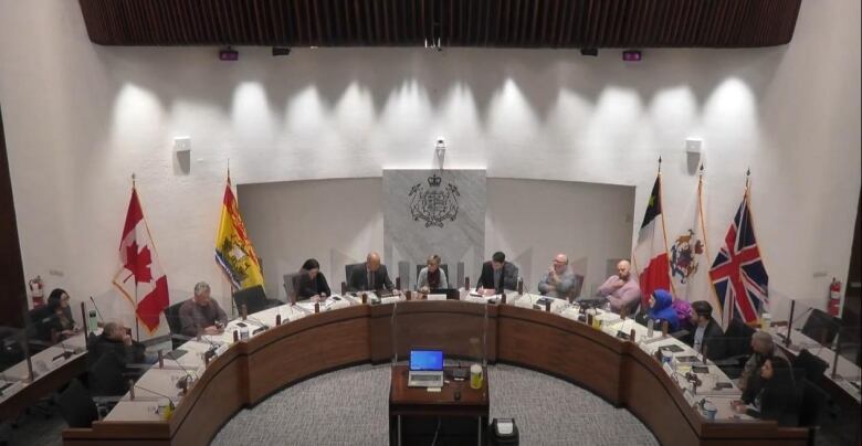 The camera looks down at a half-circle table with people sitting around it.