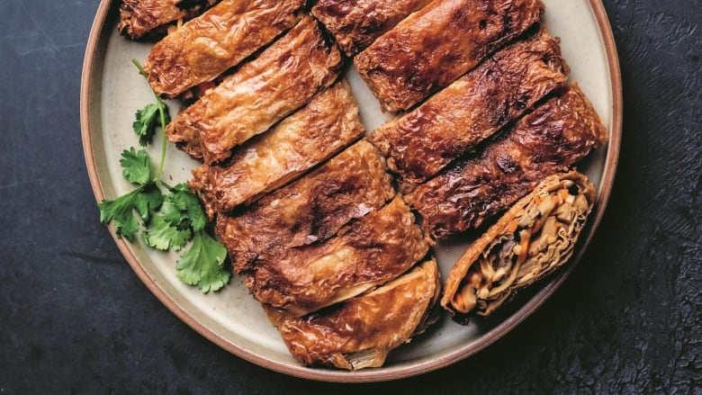 Overhead shot of a large serving plate of sliced Vegetarian Roast Goose sitting on a dark grey table. 