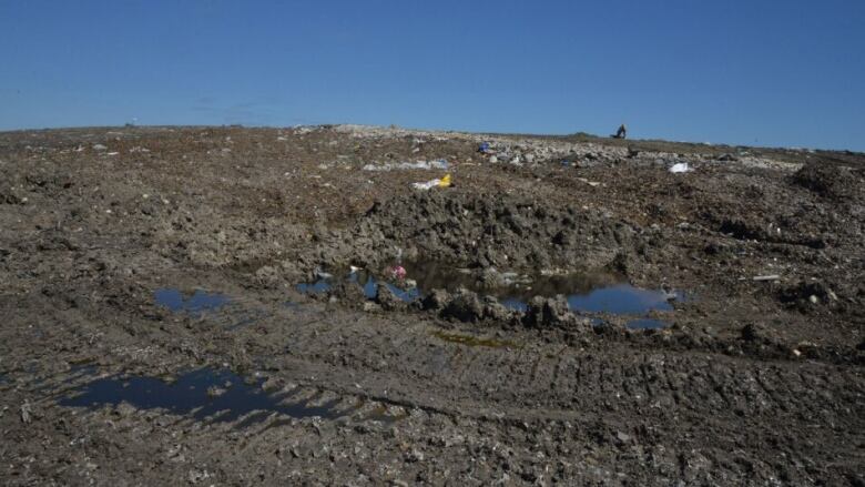 Garbage and mud spread over the ground at a landfill site.