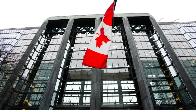 A Canada flag on a grey glass highrise.