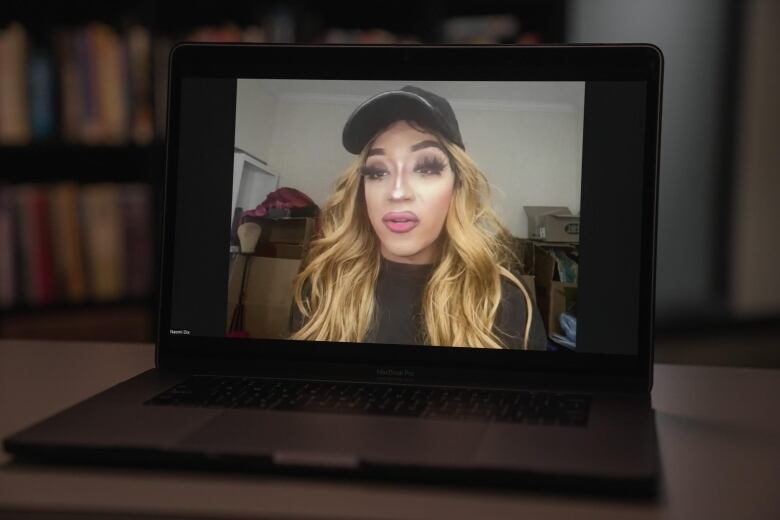 A person in bright makeup is on a computer screen.