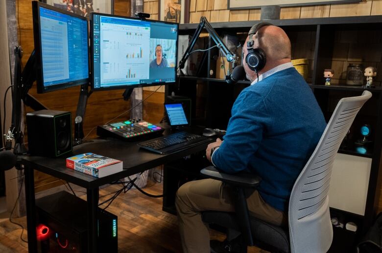 A man in front of several computer screens.