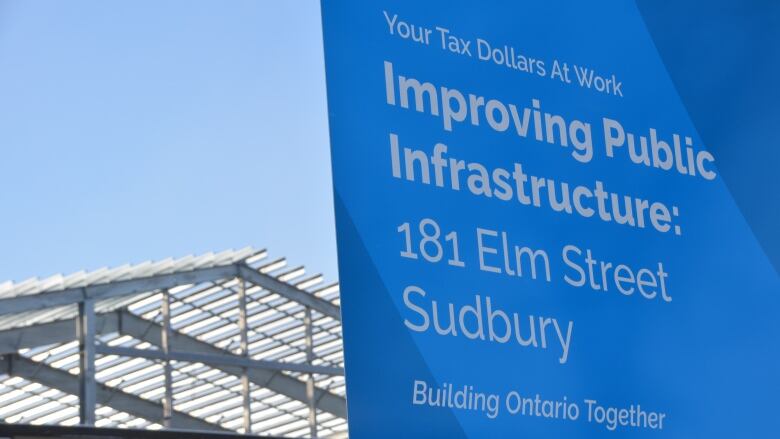 A sign outside the Sudbury Jail reads 'Your tax dollars at work' with a new roof under construction in the background 