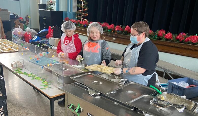 Three boys prepare meals from food trays. 