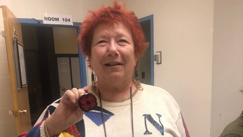 Woman smiling, holding beaded poppy.