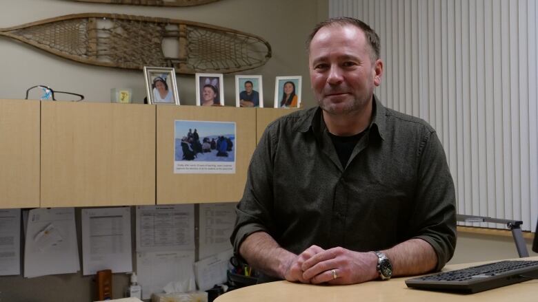 A portrait of a smiling man at a desk.