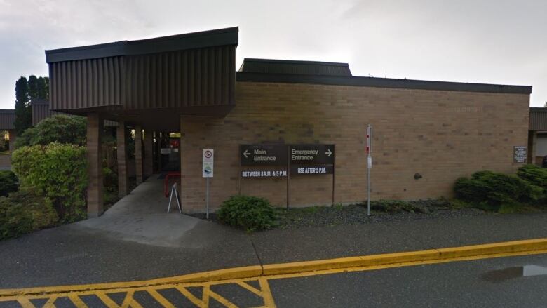 A one-storey brick building with two signs. One reads Main Entrance, and the other reads Emergency Services. 