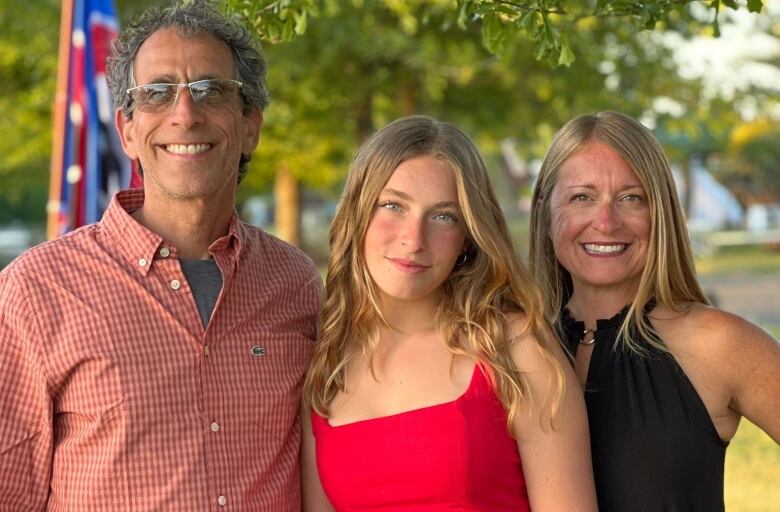 Smiling parents with teenage daughter between them.