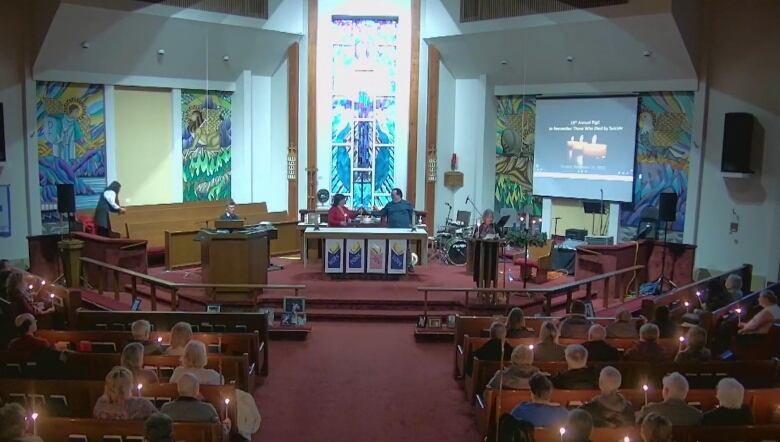 A church service is held, with parishioners holding candles. 