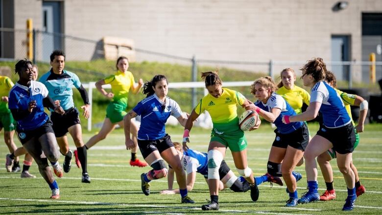 Teams of young women are playing rugby.