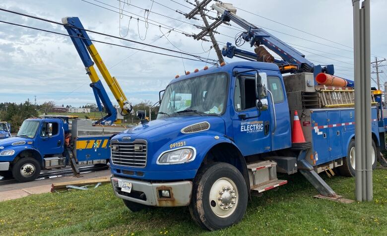 A blue Maritime Electric truck parked next to utility poles, working to restore damage after post-tropical storm Fiona