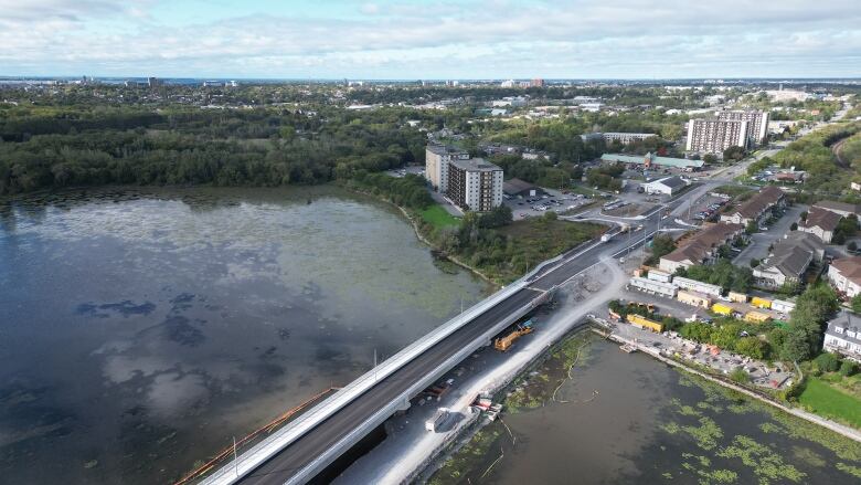 An aerial photo shows a bridge under construction crossing from a city skyline over a river.