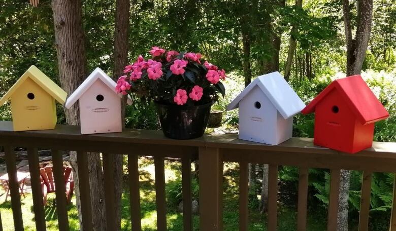 Birdhouses sit on a railing.