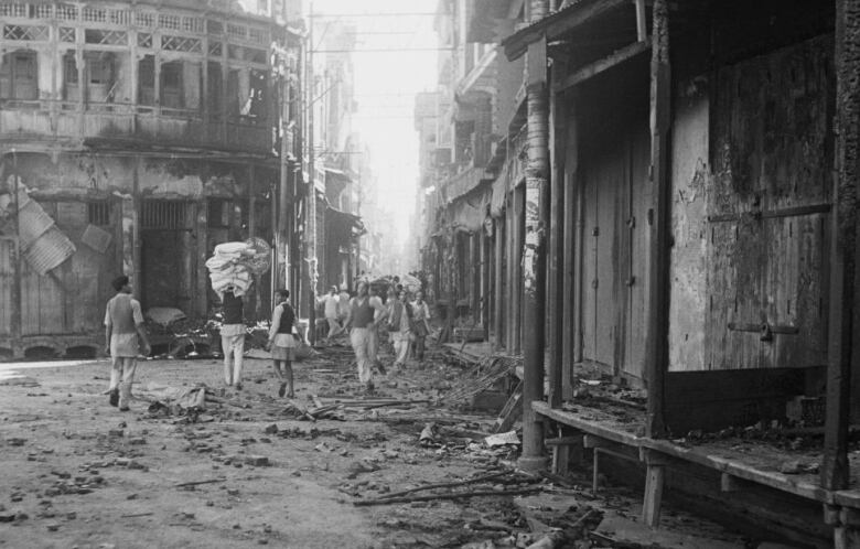 A view of the wreckage after communal riots in Amritsar, Punjab, during the Partition of British India, March 1947. People are walking through the ruins in this black and white photo. 