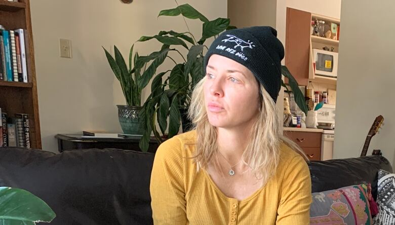 A woman sitting on a couch looks out the window in a living room. 