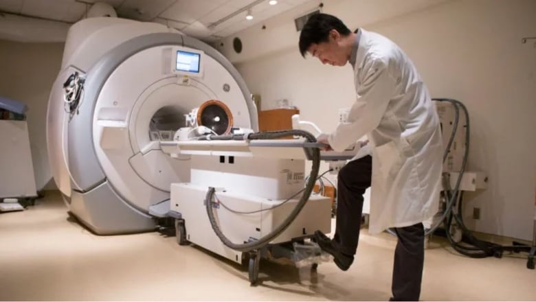 A technician tends to an MRI machine which is used for diagnostic imaging.