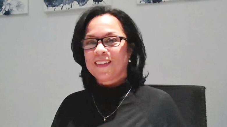 A woman with shoulder-length black hair and wearing a black turtleneck