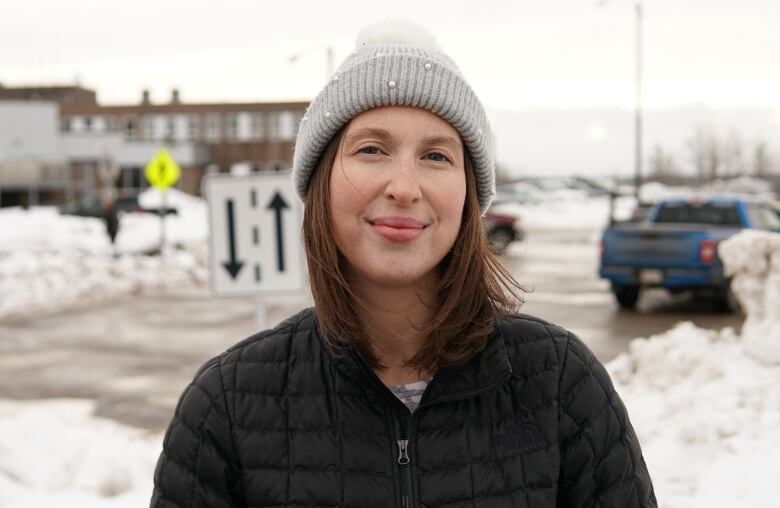 A woman wears a gray hat and black jacket.