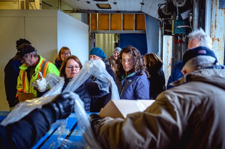 Group of men and women helping carry boxes and unpack food for delivery at a food bank warehouse in St. John's.