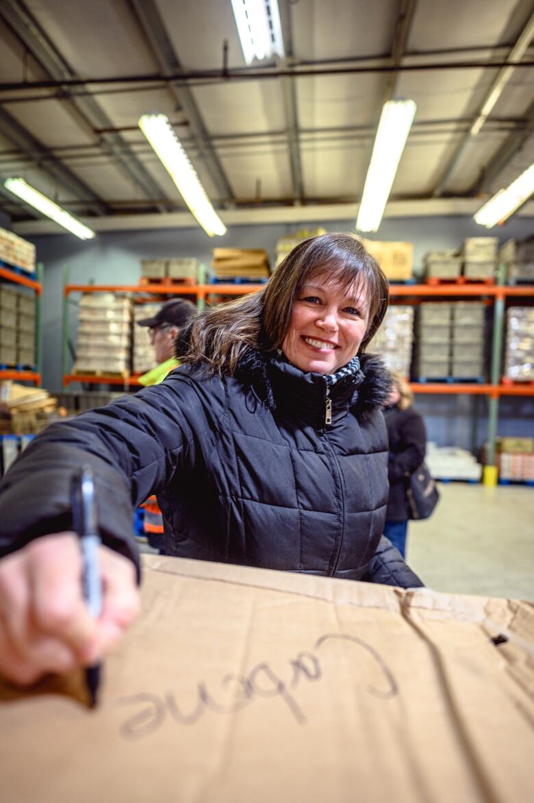 Women wearing dark blue winter coat. Smiling writing the word 