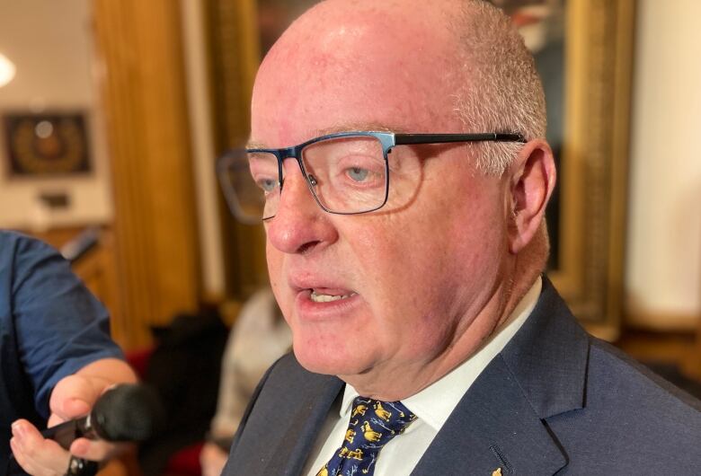 A shoulder-up photo of a man wearing glasses, with his mouth slightly open