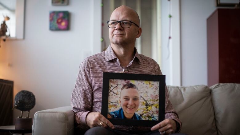 Dennis Cooper is pictured holding a picture of his child who was shot and killed by police in November in North Vancouver, British Columbia on Tuesday December 13, 2022. 