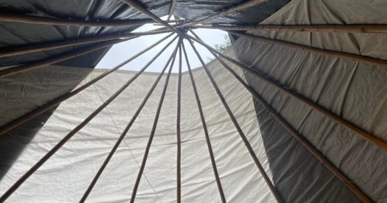 The sky can be seen in this photo looking up at a teepee.