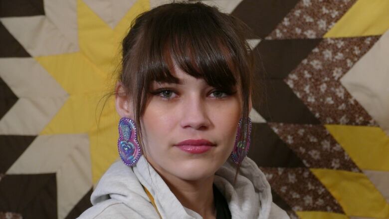 Portrait of a woman in front of a quilted blanket.