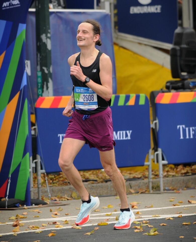 A man is running to the left in a marathon.