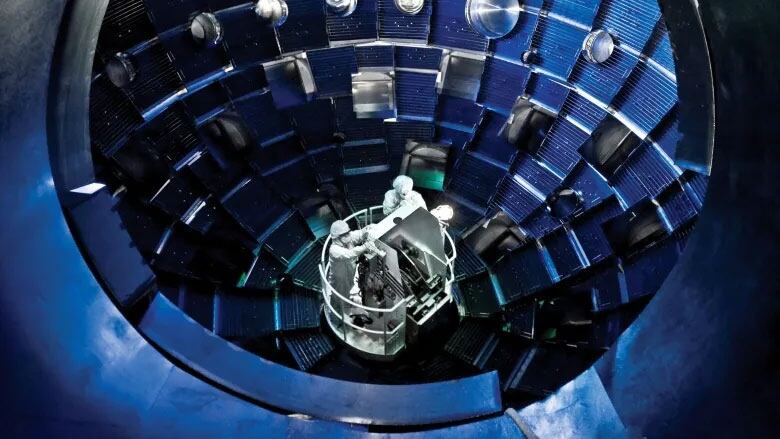 Technicians access the target chamber interior of a nuclear fusion research device.