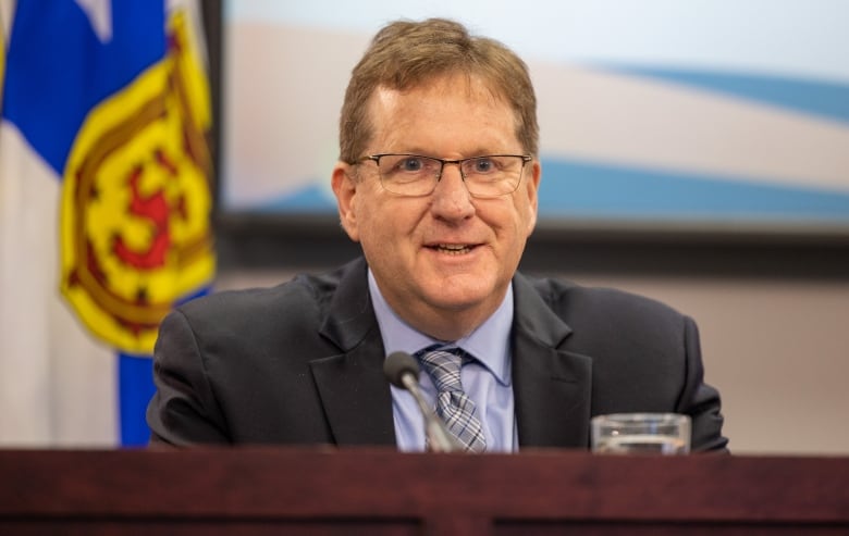 A man sits at a conference table, smiling.