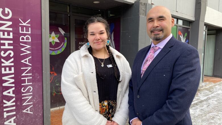 A woman and man stand outside a the front of a downtown community hub.