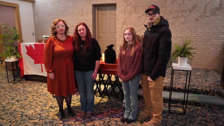 Four people stand in a Medicine Hat funeral home with an urn.