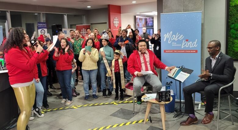 More than two dozen people cheer and clap in the lobby of CBC Calgary as host Jenny Howe announces that the fundraising goal was met. 