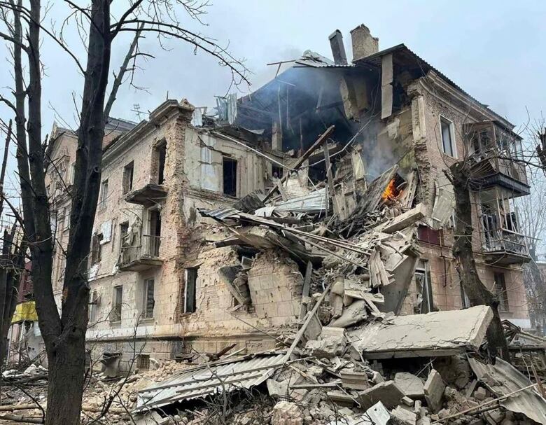 A heavily damaged building with an isolated fire is shown.