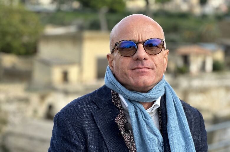 An Italian man in scarf and sunglasses.