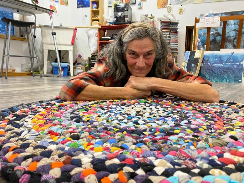 Smiling woman atop a colourful, circular rug.