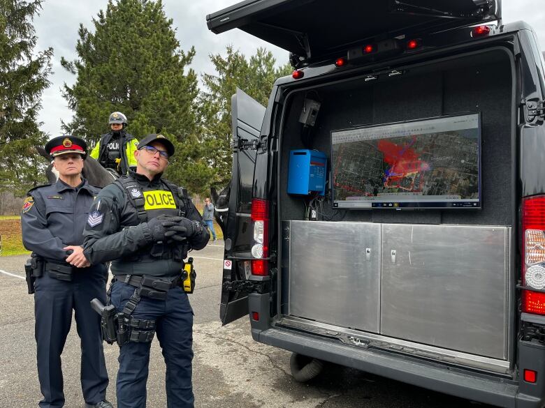 Two officers stand beside a screen that shows a map of the area where Shirley Love went missing. The map is covered in red, where the team searched for her. 